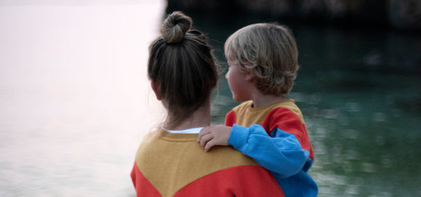 Mutter mit Kind auf dem Arm schauen im Partnerlook auf das Meer